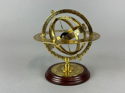 an antique brass sundial on a wooden base with a white background