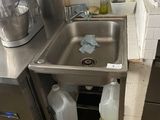 a sink in the corner of a kitchen next to a trash can