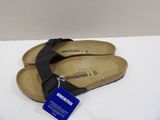 pair of black sandals with a blue tag on a white surface