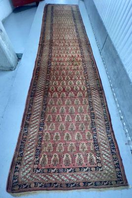 Un vieux tapis est posé par terre à côté d'une valise rouge.