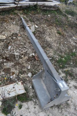 a broken piece of metal on the ground next to a pile of wood