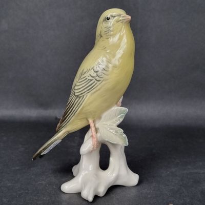 a small yellow bird sitting on a branch of a tree