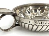 a silver bowl with a spoon in it on a white surface