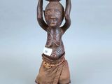 une petite statue représentant un homme tenant un bol sur la tête