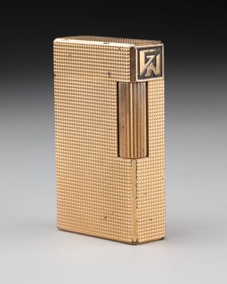 un gros plan d'un briquet doré posé sur une surface blanche