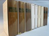 several books are lined up in a row on a white surface