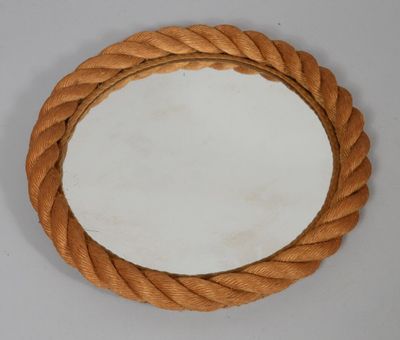 une corde enroulée autour d'un miroir rond posé sur une surface blanche