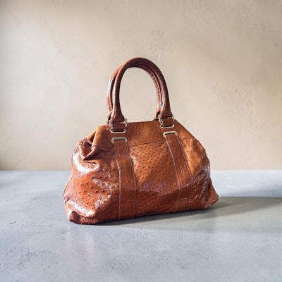 un sac à main en cuir marron posé sur une table près d'un mur