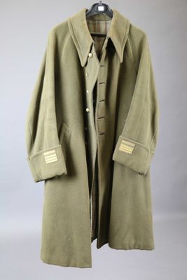 a green coat is hanging on a hanger on a wall