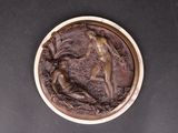 a bronze plaque depicting a woman and a goat