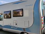 a small white and blue rv parked in a parking lot