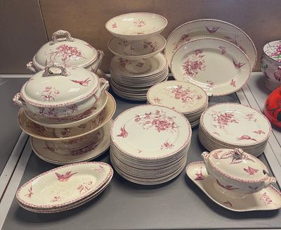 de nombreuses assiettes et bols posés sur le plan de travail, décorés de fleurs rouges