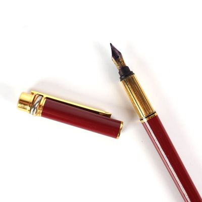 un gros plan d'un stylo plume avec une plume rouge et une plume dorée
