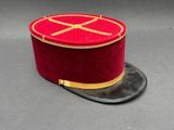 chapeau haut-de-forme en velours rouge avec une bordure dorée sur fond gris