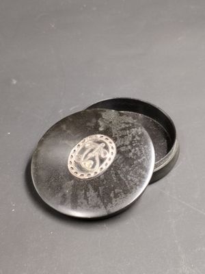 une petite boîte en métal ornée d'un motif argenté