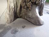 a silver statue of a man and a woman sitting on a tree stump
