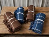 trois couvertures à carreaux bleus et marron posées sur une table en bois
