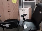 une chaise de bureau noire posée à côté d'une pile de cartons