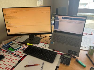 un bureau sur lequel se trouvent un ordinateur portable, un clavier, une calculatrice, une calculatrice et d'autres fournitures de bureau