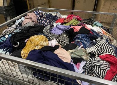 a metal basket filled with lots of clothes on the floor
