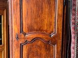 une armoire en bois posée à côté d'un lit dans une chambre