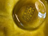 a close up of a yellow vase with a logo on it