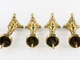 four brass candlesticks are lined up on a white surface