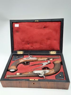 une vieille paire de pistolets dans un coffret en bois, sur fond blanc