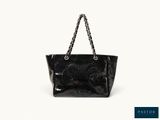 a black handbag with a chain handle and a bow on the front