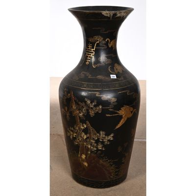 un vase noir orné de motifs dorés, posé sur une table