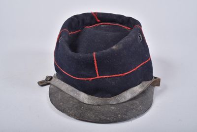 casquette bleu marine avec des surpiqûres rouges, posée sur une base métallique
