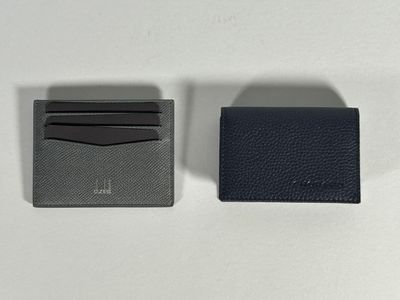 two black and grey wallets sitting next to each other on a white surface