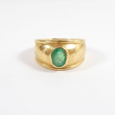 a close up of a gold ring with a green stone