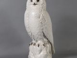 a white owl sitting on top of a tree stump