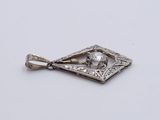 an antique silver pendant with a diamond in the center