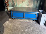 une commode bleue dans une pièce où est accroché un tableau au mur