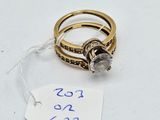 two gold rings with diamonds and a price tag on a white surface