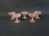quatre verres à pied roses posés sur une table noire