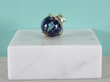un gros plan d'une bague posée sur un bloc de marbre, sur fond bleu