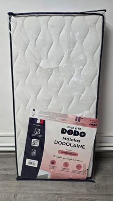 the mattress is next to a box of bedding on the floor