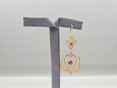 une paire de boucles d'oreilles en or ornées de pierres roses, montées sur un support