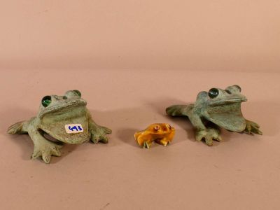 three figurines of frogs sitting on a table