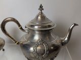 a silver tea pot and a silver tea pot on a glass table
