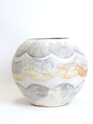 a white vase with a design on it on a white surface