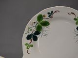 a white plate with green leaves and flowers on it