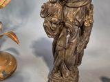 a statue of a man holding a child next to a vase of flowers