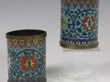 deux petits vases sont posés sur un support, sur une surface blanche