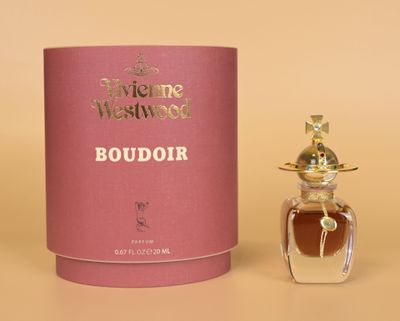une photo d'un flacon de parfum posé à côté d'une boîte rose