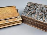 two wooden boxes with carvings on them sitting on a table