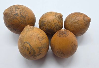 quatre boules en bois ornées de motifs, posées sur une surface blanche